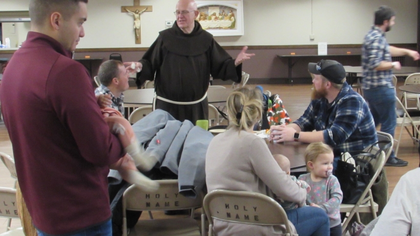 Father Patrick Gawrylewski, O.F.M., administrator of Holy Name of Jesus, engages with parents of young families at Parent Social, held after Sunday Mass on Feb. 18. (Angela Hughes photo)